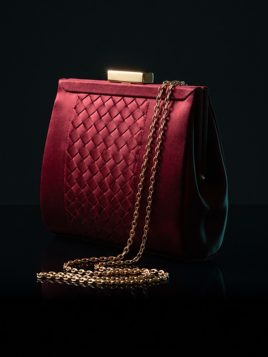 A deep-red woven satin clutch with a gold clasp and chain.