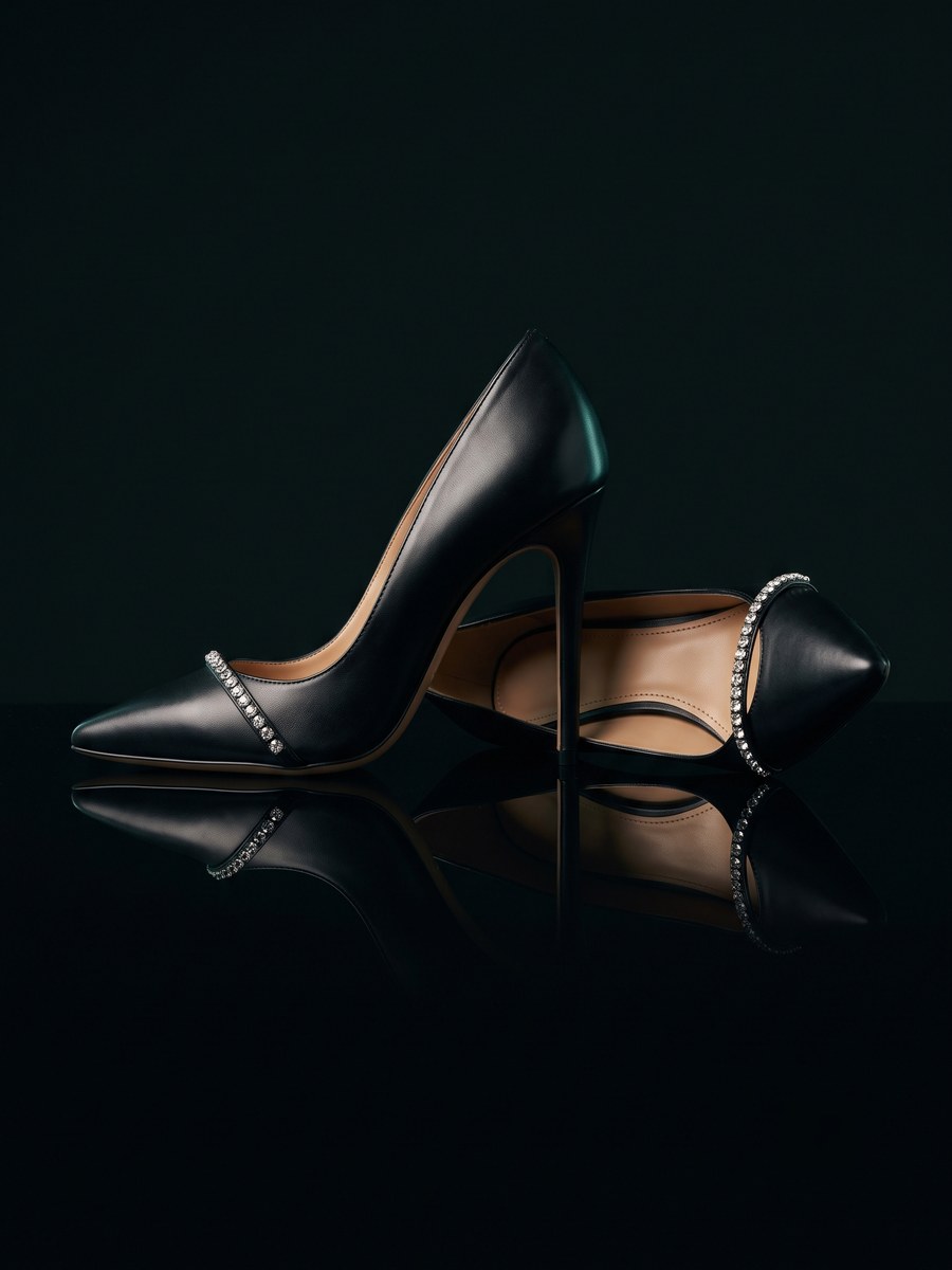 A pair of black pointed-toe stiletto pumps with crystal detail.